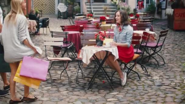 Девушка встречается с друзьями в кафе на открытом воздухе — стоковое видео