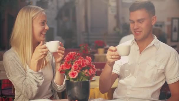 Νέοι χαμογελώντας ζευγάρι στην εξωτερική καφετέρια — Αρχείο Βίντεο