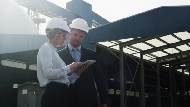 Los gerentes en sombreros duros están hablando y usando Tablet PC en entornos industriales — Vídeo de stock