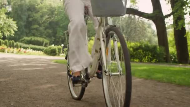 Mujer adulta feliz está montando bicicleta en el parque — Vídeo de stock