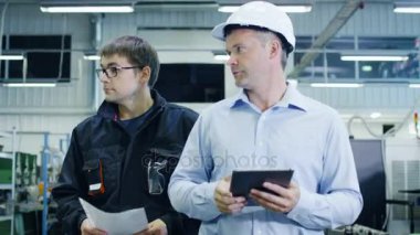 Mühendis içinde kask ve fabrika işçisi üretim tesisi ile yürüme