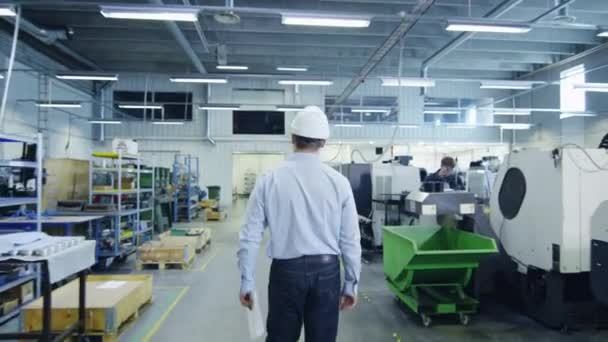 Ingenieur mit Hut läuft durch die Fabrik und begrüßt einen Arbeiter — Stockvideo