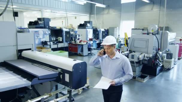 Ingenieur mit harter Mütze telefoniert in Fabrik. — Stockvideo