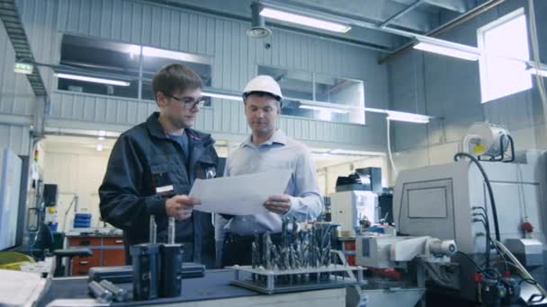 Ingeniero en casco duro y trabajador de fábrica están hablando de Blueprint — Vídeos de Stock