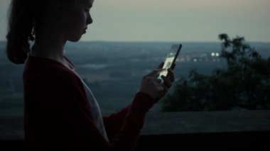 Kız kullanarak cep telefonu açık havada akşam olduğunu.