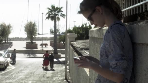 Chica joven está usando teléfono en las calles de la ciudad . — Vídeo de stock