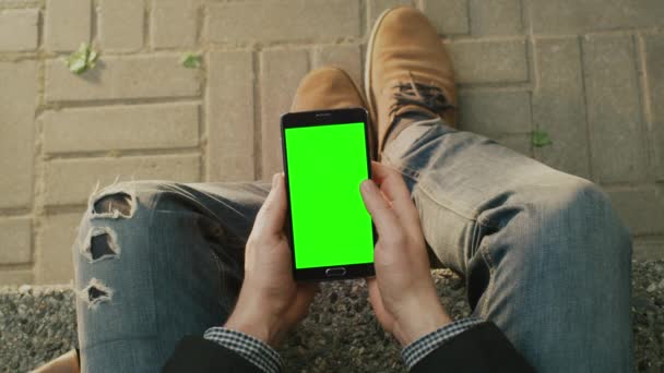 Mann benutzt Androidtelefon auf dem Schoß im Freien an sonnigen Tagen. Mehr dazu lesen Sie hier — Stockvideo