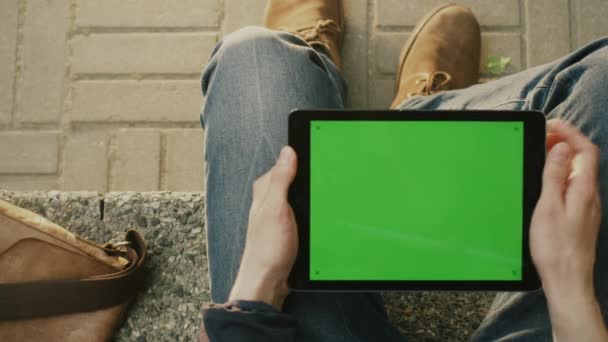 Mens is met behulp van Tablet in Landscape-modus op schoot buiten op een zonnige dag. POV — Stockvideo