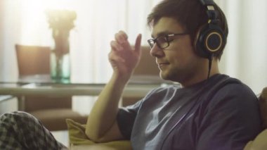 Adam evde müzik dinliyor.