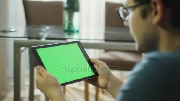 Man is Holding Tablet with Green Screen in Landscape Mode at Home. — Stock Video