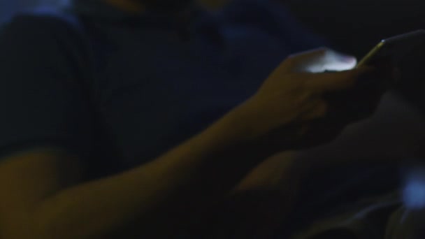 El hombre está tomando el teléfono de la mesa para escribir un mensaje por la noche — Vídeo de stock