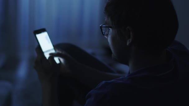 El hombre está escribiendo un mensaje en el teléfono Android por la noche — Vídeos de Stock