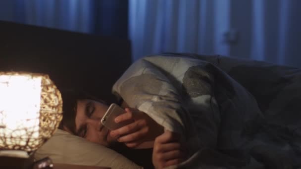 Ο άνθρωπος χρησιμοποιώντας τηλέφωνο πριν πάει για ύπνο και εναλλαγή Off φως τη νύχτα — Αρχείο Βίντεο