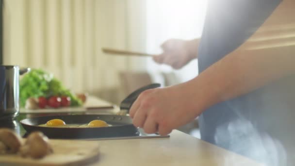 El hombre prepara huevos fritos por la mañana — Vídeos de Stock