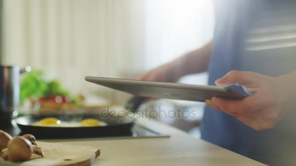 Человек использует планшетный компьютер при подготовке пищи — стоковое видео