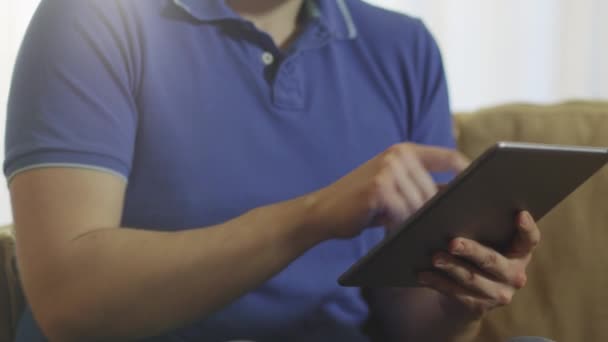 Az ember ül a kanapén, és segítségével tabletta — Stock videók