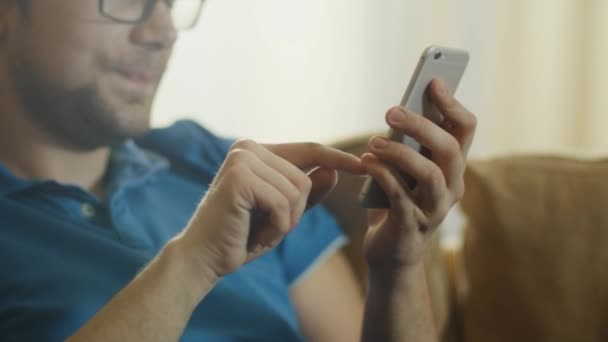 L'uomo è seduto sul divano e utilizzando il telefono cellulare — Video Stock