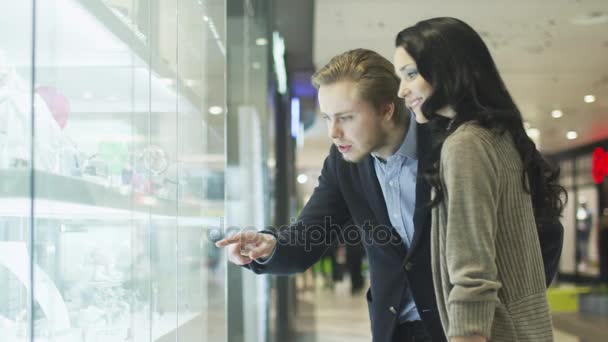 Молодая пара рассматривает витрину ювелирного магазина в торговом центре . — стоковое видео