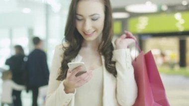 Genç esmer kız güzel mükemmel gülümseme ile cep telefonu kullanarak alışveriş merkezi var. El atış.