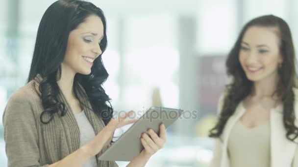 Duas meninas estão usando Tablet no lugar público . — Vídeo de Stock