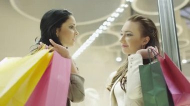 İki mutlu ve gülümseyen kız alışveriş merkezinde konuşma Asansör var