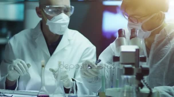 Команда ученых проводит химические исследования и эксперименты в лаборатории — стоковое видео