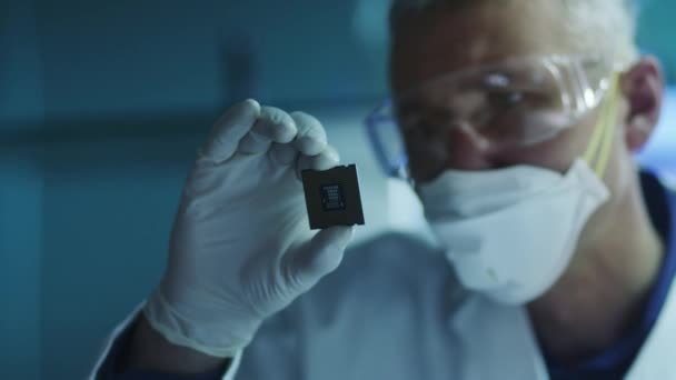 Компьютерный инженер держит и проверяет чип процессора — стоковое видео