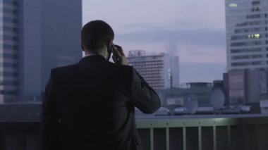İşadamı çatıda olurken telefonda