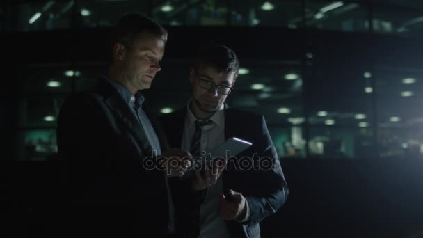 Zwei Geschäftsleute unterhalten sich am Abend. Einer hält Tablet in der Hand. — Stockvideo