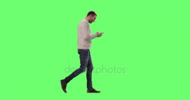 Beyaz Casual adam yürüyüş ve bir mock-up smartphone kullanarak arka planda yeşil ekran.