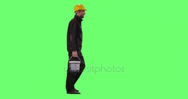 Bir sabit Hat taşıyan boya kovası inşaat işçisi bir Mock-up yeşil ekran arka planda üzerinde yürüyor.