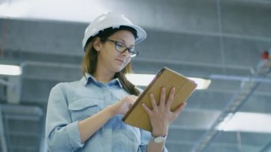 Bir sabit Hat kullanır Tablet bilgisayarda büyük fabrika içinde yürüyüş sırasında kadın mühendis.