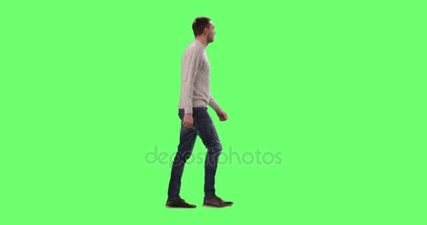 Casual caucásico hombre está caminando en un simulacro de pantalla verde en el fondo . — Vídeos de Stock