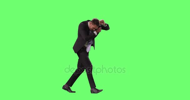 Podnikatel v obleku chůzi proti silnému větru se snaží pokrýt jeho tvář s Arm. Shot na obtahování zelená obrazovka. — Stock video