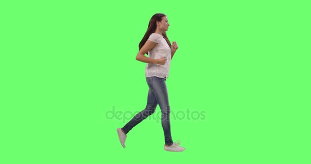 Fitte junge Mädchen in lässiger Kleidung, die auf einer grünen Leinwand-Attrappe laufen. — Stockvideo