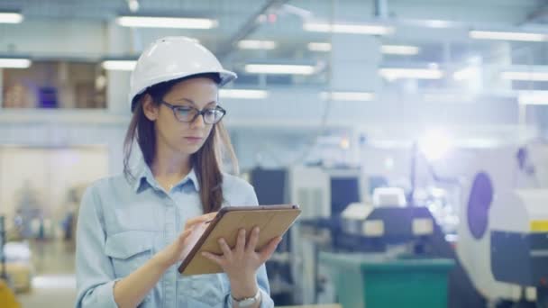 Vrouwelijke industrieel ingenieur in een Hard Hat gebruikt Tablet PC terwijl Walking in grote fabriek. — Stockvideo