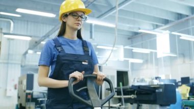 Güzel kadın işçi kask palet Lifter büyük bir fabrika binası içinde çalışır.