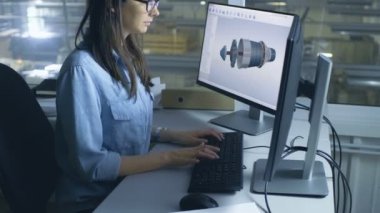 Kadın mühendis Cad yazılımı 3d türbin/motoru modelde masaüstü bilgisayarında çalışır. Fabrika içinde gördün mü--dan Her ofis pencere olduğunu.