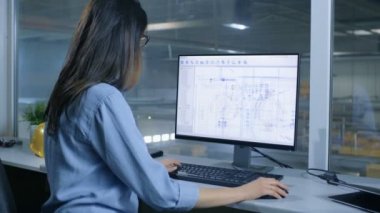 Teknik planları ile kişisel bilgisayarında çalışan kadın endüstri mühendisi. Fabrika içinde gördün mü--dan Her ofis pencere olduğunu.