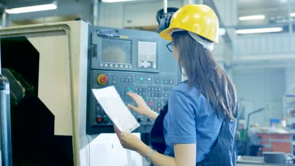 Επαγγελματία χειριστή θηλυκό σε σκληρό καπέλο ρύθμιση επάνω / προγραμματισμό Cnc μηχανή με τη βοήθεια του πίνακα ελέγχου. Μεγάλο βιομηχανικό εργοστάσιο είναι ορατό. — Αρχείο Βίντεο