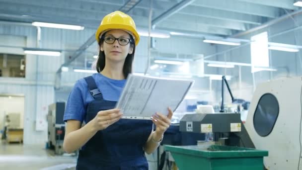 Bella operaia industriale femminile cammina e legge documenti nel grande edificio di fabbrica . — Video Stock