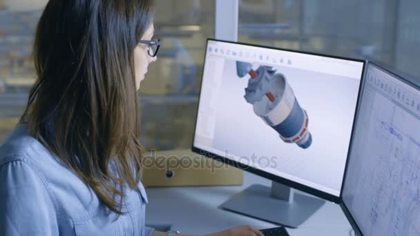 女性の工業エンジニアは、デスクトップ コンピューターの Cad ソフトウェアで 3 d のタービン ・ エンジン モデルで動作します。工場の中は彼女の事務所窓から見て. — ストック動画