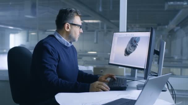 Hoofdingenieur van de man bezig met grote technische Project maken 3d Turbine / motor Model op zijn PC. Hij maakt gebruik van CAD-Software.Out van de Office-venster grote fabriek wordt gezien. — Stockvideo