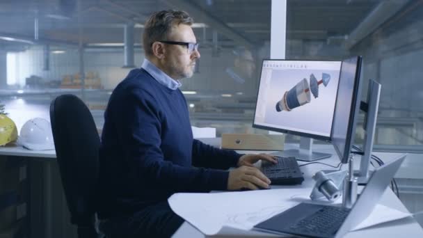 Manliga maskinchef arbetar på stora tekniska projekt Skapa 3d turbin / motor modell på hans dator. Ses han använder Cad Software.Out av Office fönster stora fabriken. — Stockvideo