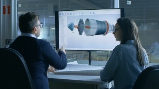 Mannelijke en vrouwelijke ingenieurs werk met blauwdrukken terwijl de presentatie wordt weergegeven 3D-Model van een motoronderdeel dat Turbine /. In achtergrond functionele Plant wordt gezien. — Stockvideo