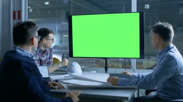 Mérnökök csapata van fontos találkozó. Bemutató a kijelzőn modell zöld képernyő. A háttér-gyárban látható. — Stock videók