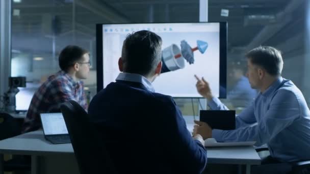 Das Team der Wirtschaftsingenieure diskutiert die Konstruktion von Turbinen- und Triebwerksteilen in 3D, die auf einem Präsentationsdisplay gezeigt wird. Im Hintergrund ist die Fabrik zu sehen. — Stockvideo