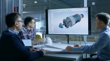 Endüstri Mühendisleri ekibi tartışmak 3d Model türbin / motoru bir sunum ekranında gösterilen tasarım. Arka plan fabrikada görülür.