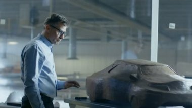 Şef otomotiv tasarımcısı komisyon ile hamuru kil modelden futuristik araba Sculpts. O bir büyük araba fabrikasında bulunan özel bir stüdyoda çalışıyor.