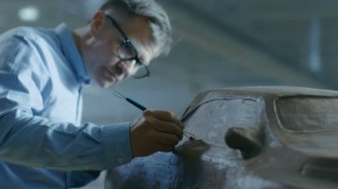Şef otomotiv tasarımcısı komisyon ile hamuru kil modelden futuristik araba Sculpts. O bir büyük araba fabrikasında bulunan özel bir stüdyoda çalışıyor.